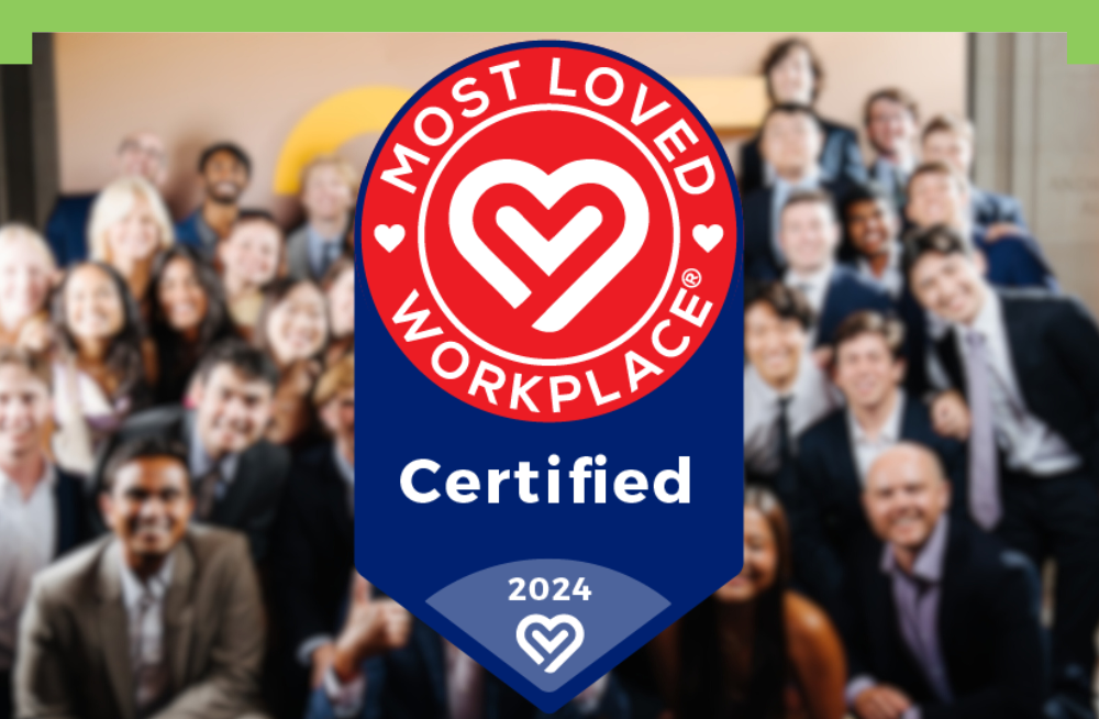 An award shield reads: “Most Loved Workplace Certified.” Behind the shield is a blurred background of a large group of smiling men and women.