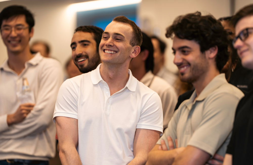 A group of smiling employees, within a larger crowd of people.