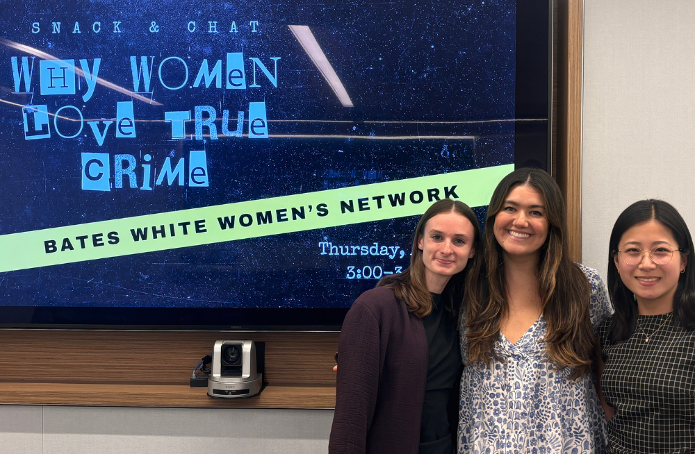 Three young women stand together smiling at the camera. A screen behind them reads: "Snack & Chat: Why Women Love True Crime."